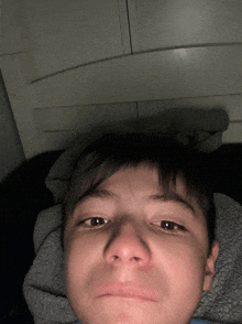 a boy laying on a bed with a blanket on his head