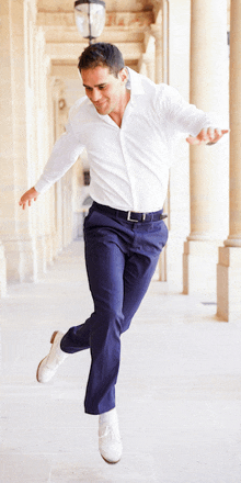 a man in a white shirt and blue pants is jumping