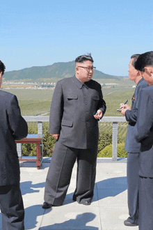 a man in a suit and glasses stands in front of a group of men