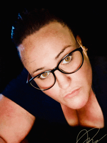 a woman with glasses and a tattoo on her forehead looks down