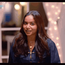 a woman wearing a cross necklace and a denim shirt