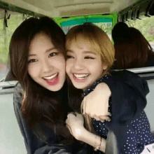 two girls are hugging each other in a car .