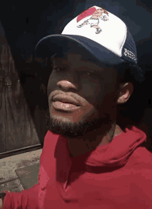 a man wearing a red hoodie and a white trucker hat