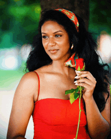 a woman in a red dress is holding a rose