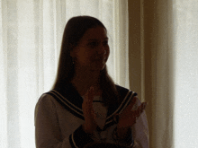 a girl in a white and blue uniform is clapping her hands