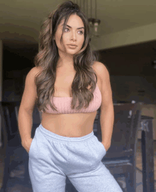 a woman in a pink crop top and grey sweatpants