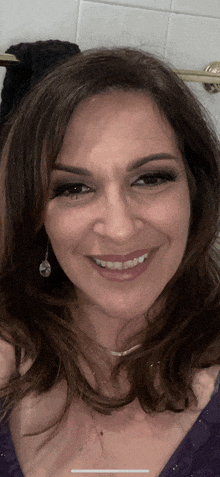 a woman in a purple dress and earrings smiles for the camera