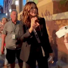 a woman wearing a lanyard that says ' a ' on it walks down the street