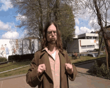 a man with long hair and glasses stands in front of a building that says ' amsterdam ' on the front