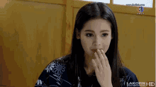 a woman is covering her mouth with her hand while watching a lakorn hd show