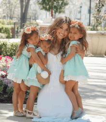 a woman in a white dress is surrounded by three little girls in mint green dresses