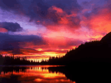 a colorful sunset over a lake with trees in the background