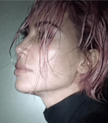 a close up of a woman 's face with pink hair and a black shirt