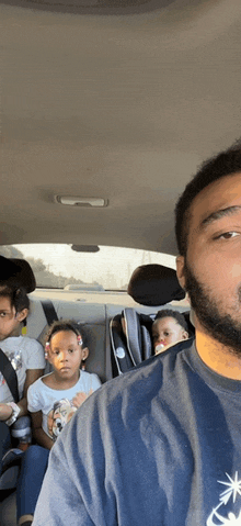 a man sitting in a car with three children