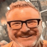 a man wearing glasses and a beard is smiling .