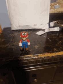 a mario figure is sitting on a counter next to a white envelope