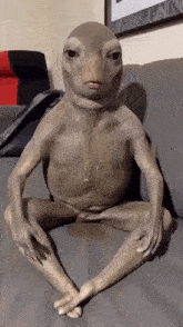 a frog with a human body is sitting on a couch with its legs crossed .