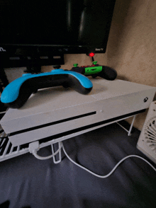 a white xbox one with a blue controller on top