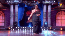 a woman in a black saree is dancing on a stage with a sign above her that says freedom