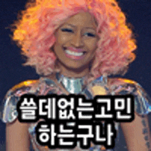 a woman with pink hair is smiling and wearing a wig and a metallic outfit .