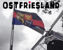 a windmill with a flag on top of it and the words ostfriesland on the bottom