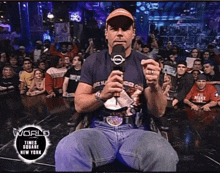 a man sitting in front of a crowd with a world times square new york logo