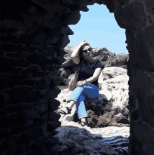 a woman sits on a rock in a cave with her hand on her head