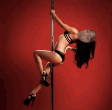 a woman in a black bikini is dancing on a pole with her eyes closed