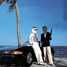 a man and a woman are standing next to a car on a beach