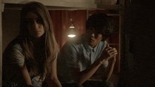 a man and a woman sit under a bunk bed