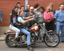 a man is riding a harley davidson motorcycle with two people on it