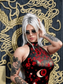 a woman with white hair and tattoos is standing in front of a dragon .