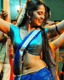 a woman in a blue crop top and blue saree is smiling