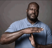 a man in a blue shirt is making a stop gesture