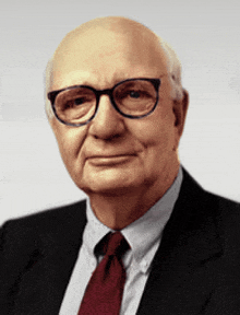 a man wearing glasses and a suit and tie looks at the camera