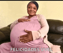 a pregnant woman is sitting on a couch with the words felicidades uvel written on the bottom