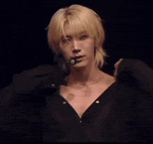 a man with blonde hair is wearing a black shirt with a microphone on his neck
