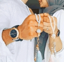 a man and woman are holding hands and holding rosary beads .