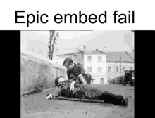 a black and white photo of two men laying on the ground with the caption epic embed fail