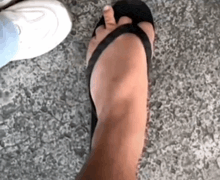 a close up of a person 's foot wearing a black flip flop and a white shoe .