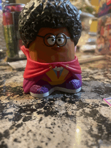 a cartoon character with glasses and a cape is sitting on a table