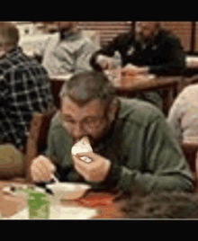 a man with a beard is sitting at a table eating food