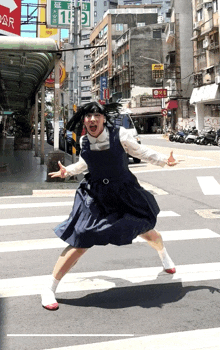 a woman in a blue dress is crossing a street in front of a sign that says 1 and 9