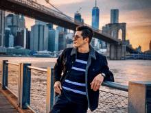 a man leans against a railing in front of a bridge