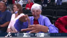 an elderly woman is sitting in a stadium watching a game between the atlanta braves and the san francisco giants