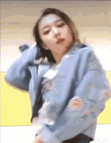 a woman in a blue jacket is dancing and looking at the camera .