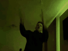 a man in a black shirt is standing in a dark room with his arms outstretched