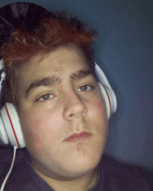 a young man wearing headphones looks at the camera with a sad look on his face