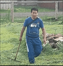 a man in a kfc shirt is mowing grass with a rake