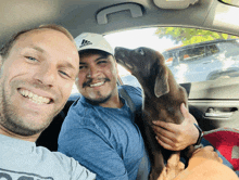 a man wearing a white adidas hat holds a brown dog